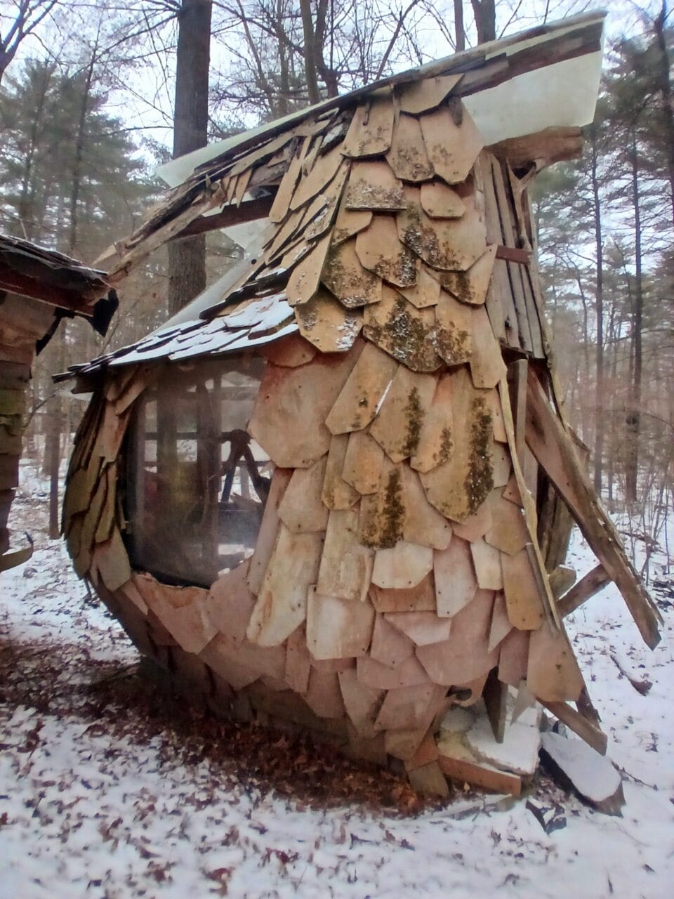 a hand-built shed-like structure in a snowy wooded landscape, part of "B-Home," a collection of intuitively built structures from salvaged materials