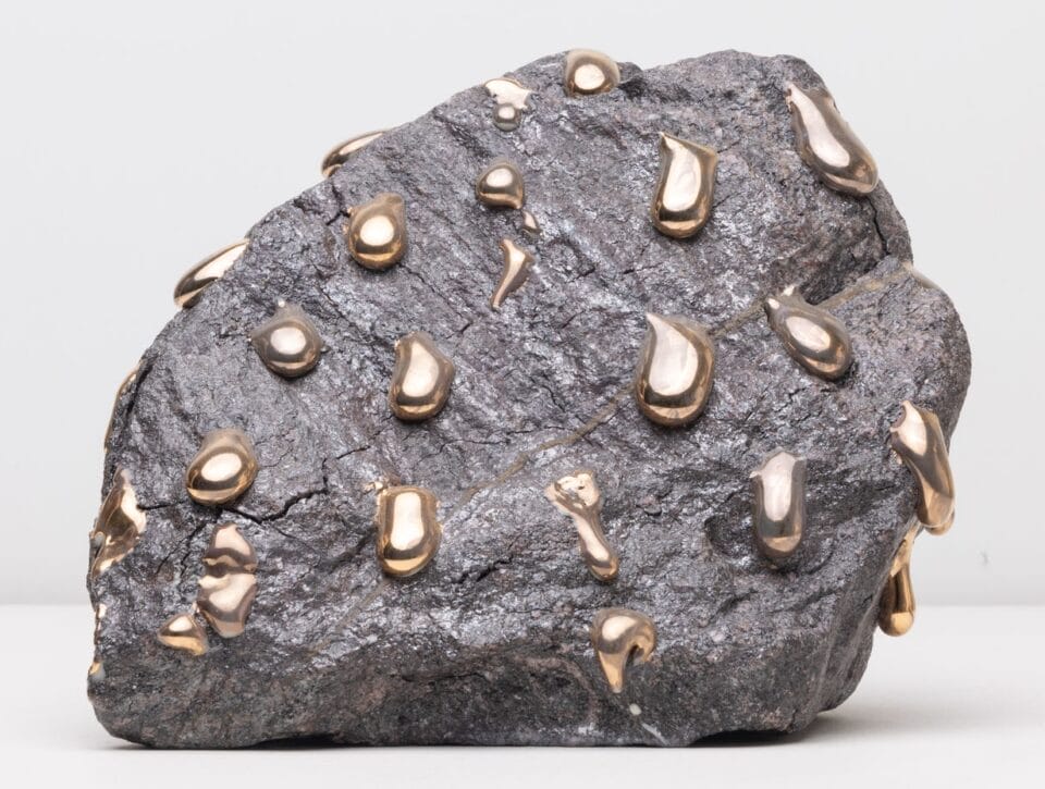 a gray stone like form covered in gold drips