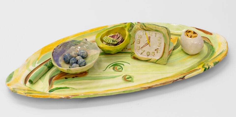 a green tray with ceramic objects like little dishes and a clock