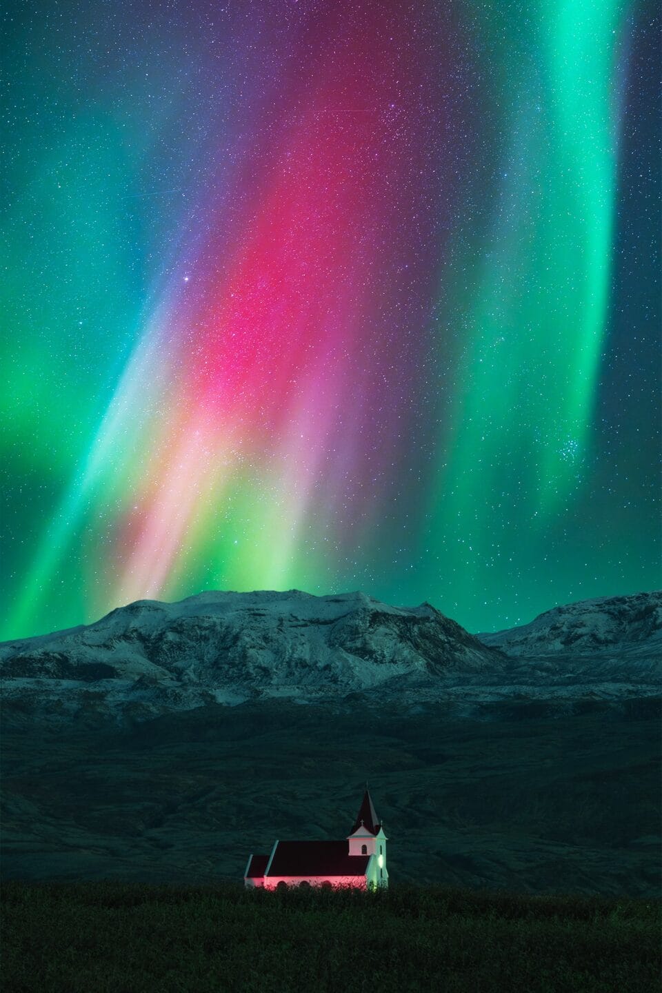 a small, isolated church glows with the colors of the Northern Lights in the sky above