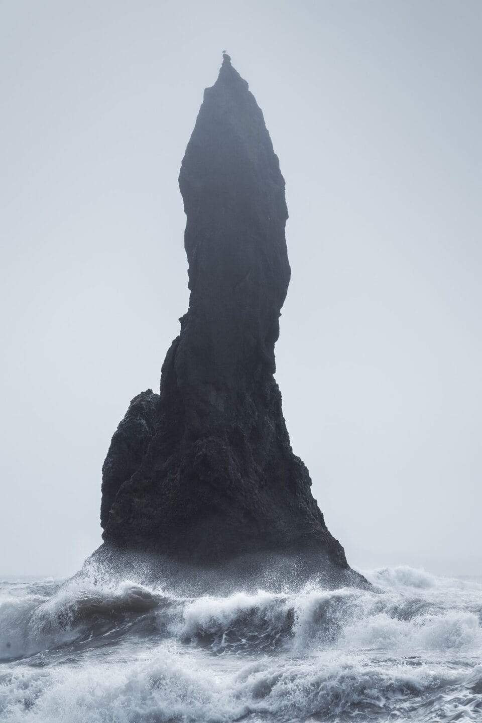 a tall and vertical cliff, isolated by raging waters