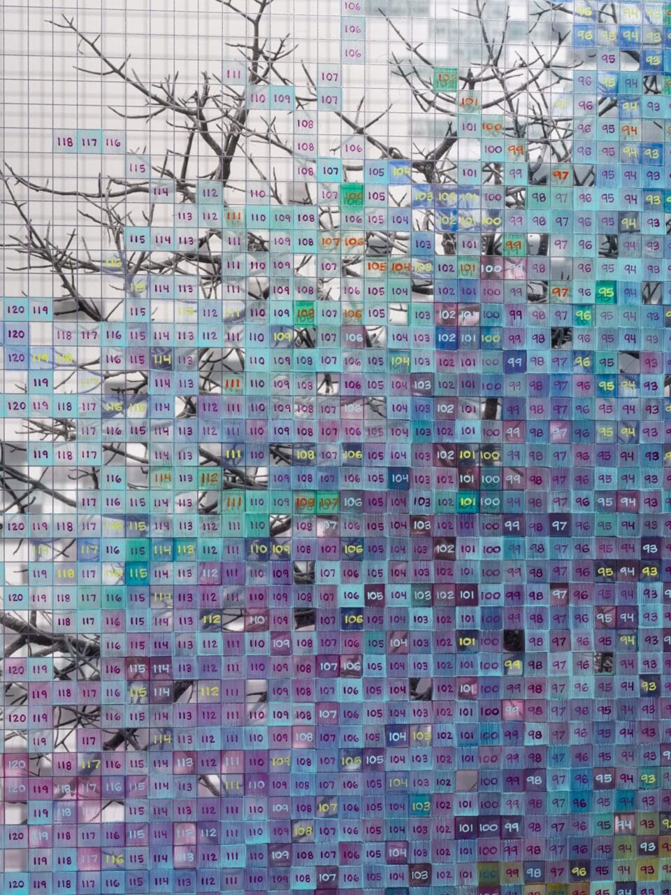 Detail of a a grayscale tree layered atop a blue and purple  numbered grid with a shadow of a tree printed on it