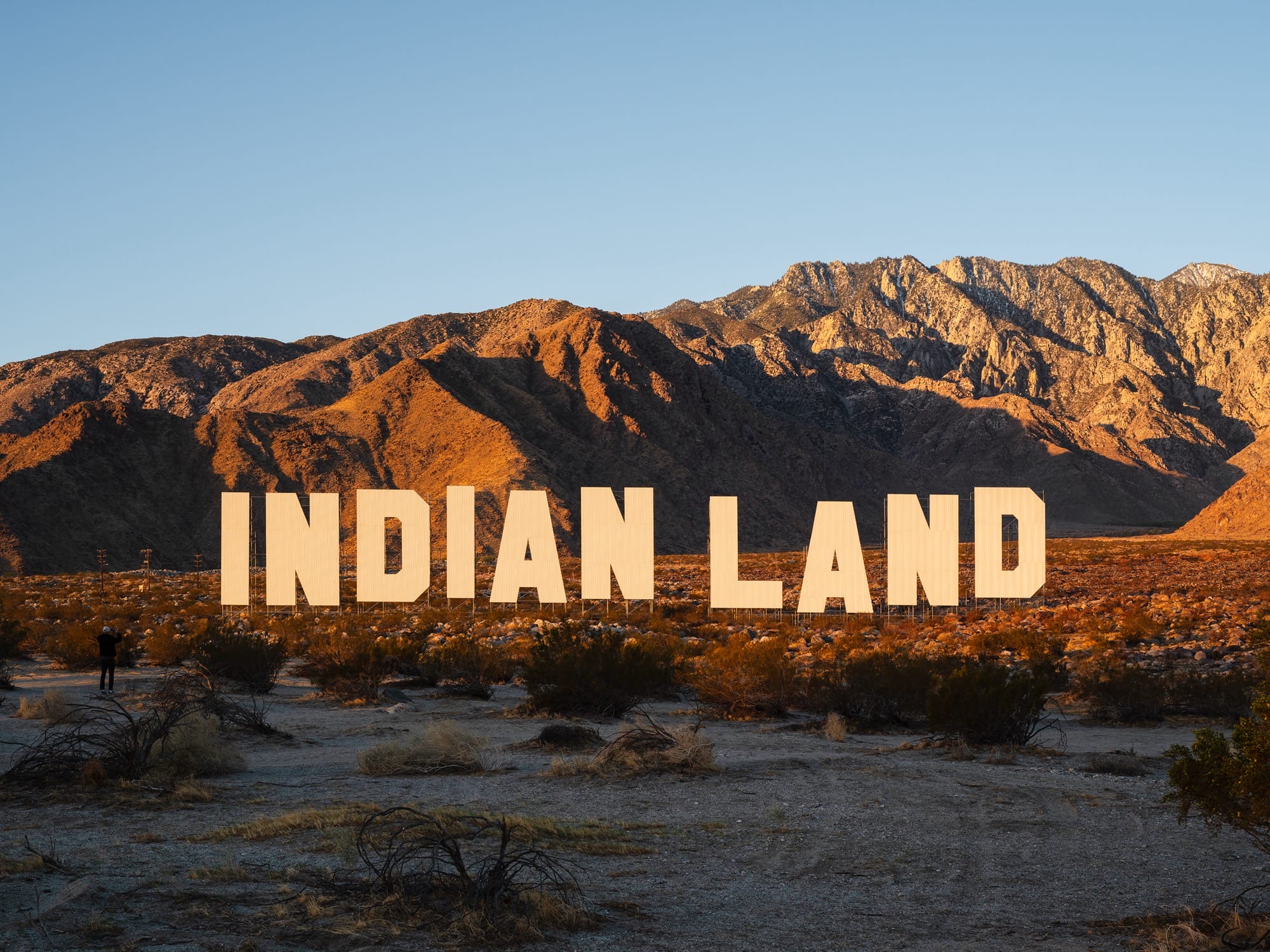 a large-scale installation in the desert resembling the Hollywood sign that reads "INDIAN LAND"