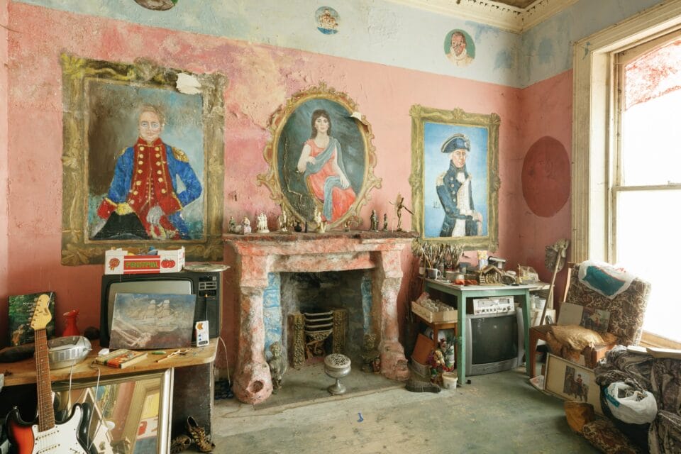 the interior of Ron Gittins' apartment in Birkenhead, England, the walls of which are painted with a colorful, romantic mural of painted portraits above an ornate fireplace