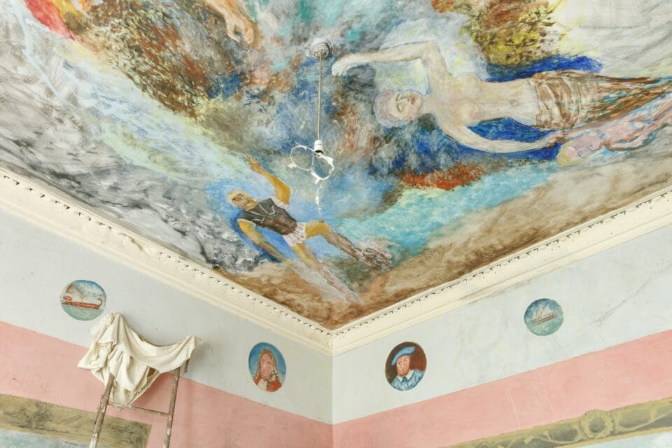 the interior of Ron Gittins' apartment in Birkenhead, England, of the ceiling of which is painted with a colorful, romantic mural, with portraits in tondos along the trim at the top