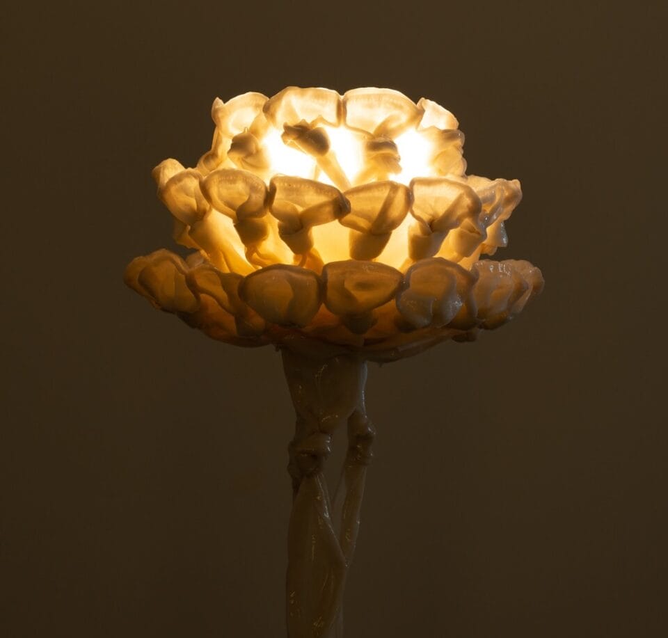 the top of a sculptural lamp, illuminated in the dark, made from twisted pieces of fabric coated in bio resin and knotted