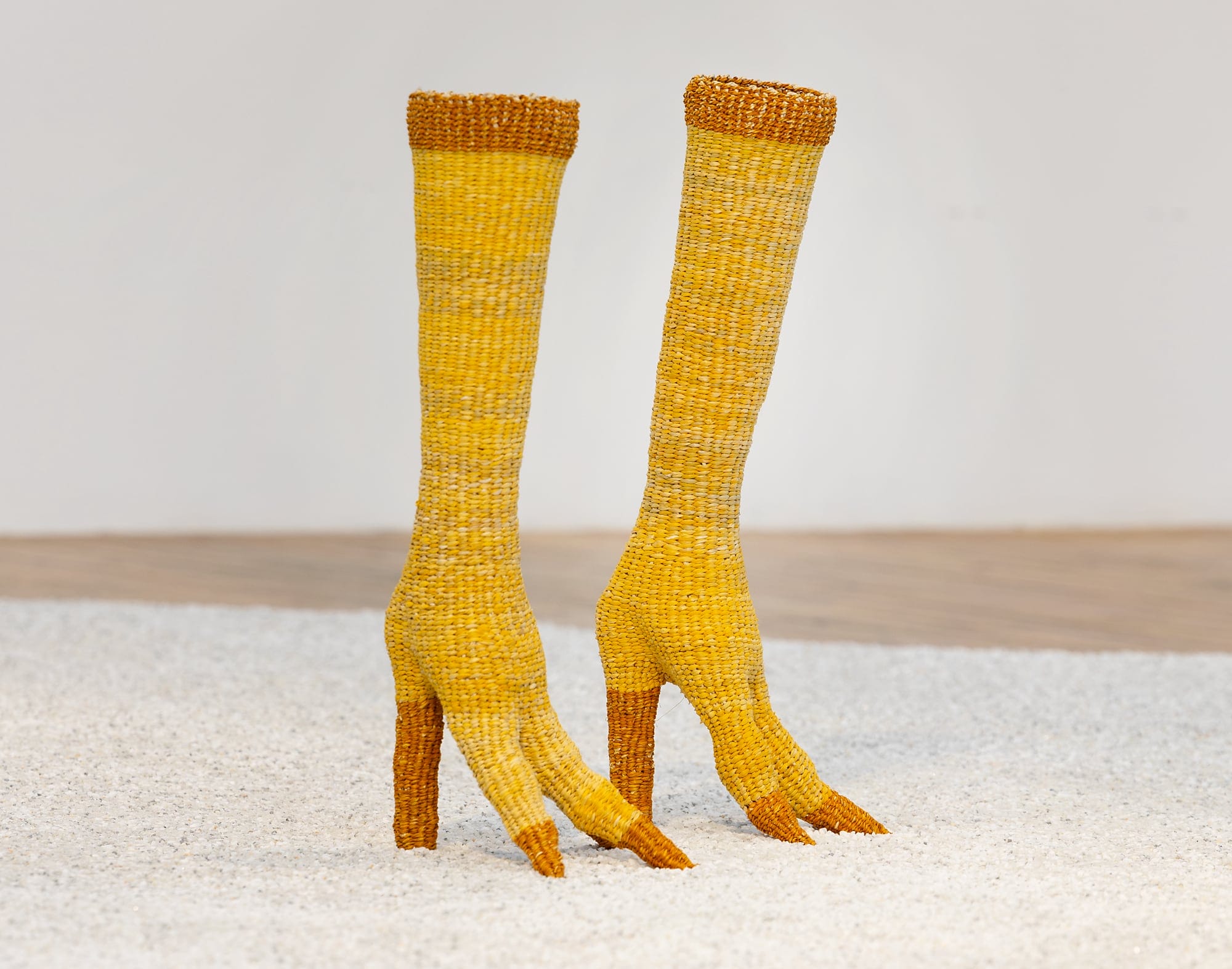 a pair of yellow woven straw boots shaped like bird legs