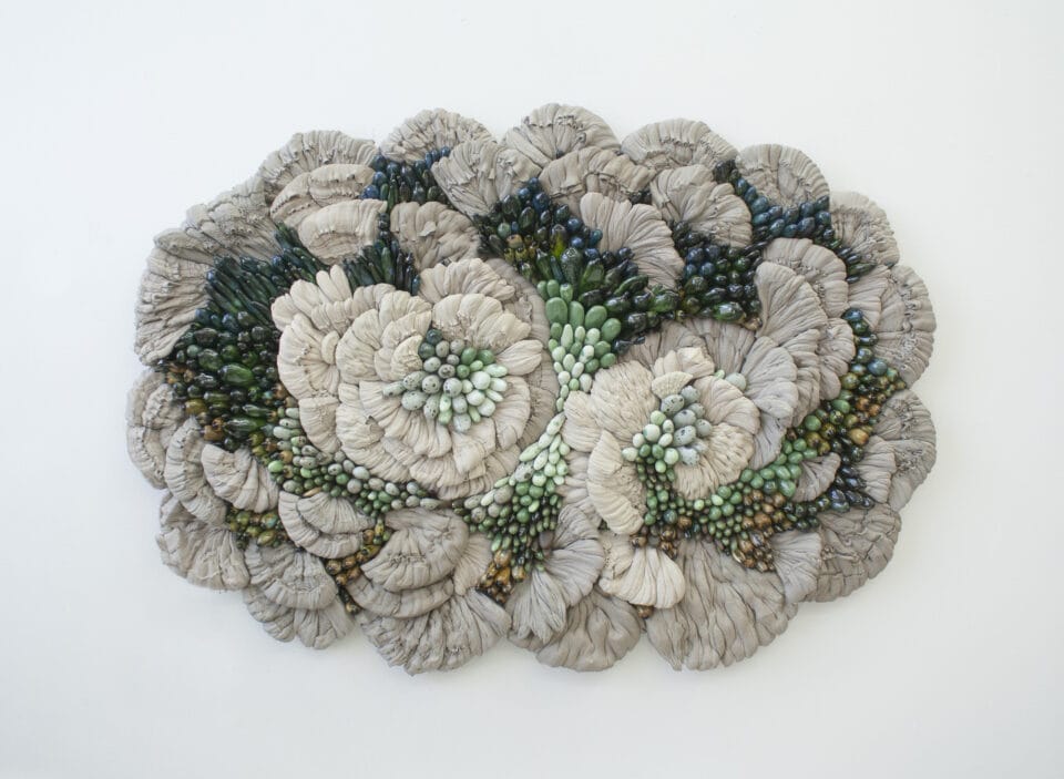 a wall-mounted sculpture of a cluster of botanical forms made from glass, wood, and ceramics