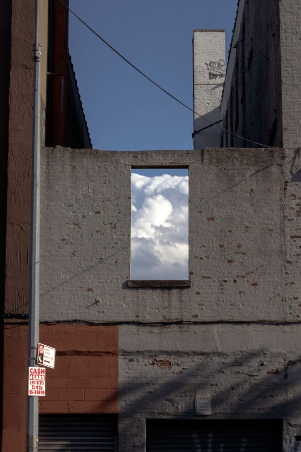 a vertical photograph of clouds captured through a window of a building