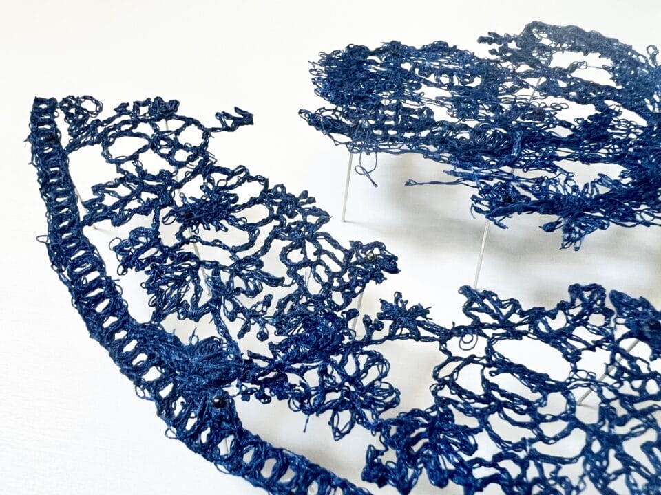 a detail of a lacework art piece of a blue-and-white porcelain motif on a white background