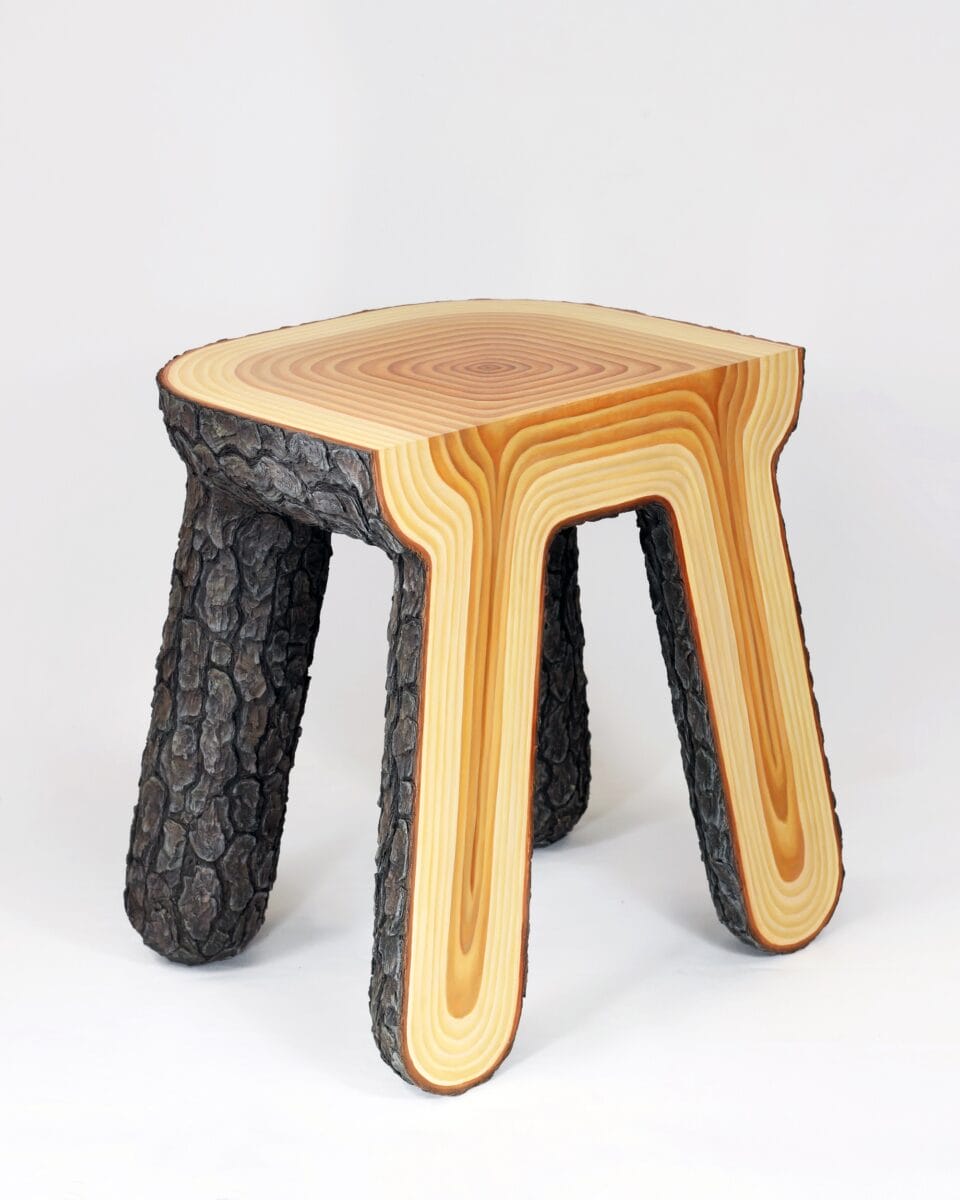 a sculptural stool that looks as though it has been carved directly out of the middle of a tree, with bark on one side