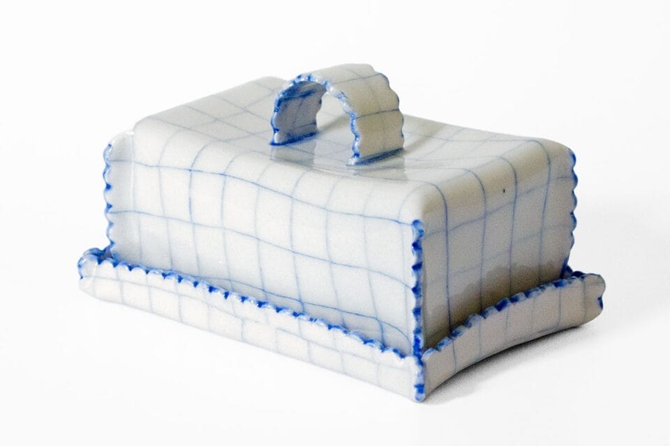 a ceramic butter dish that appears to be made of blue lined white graph paper