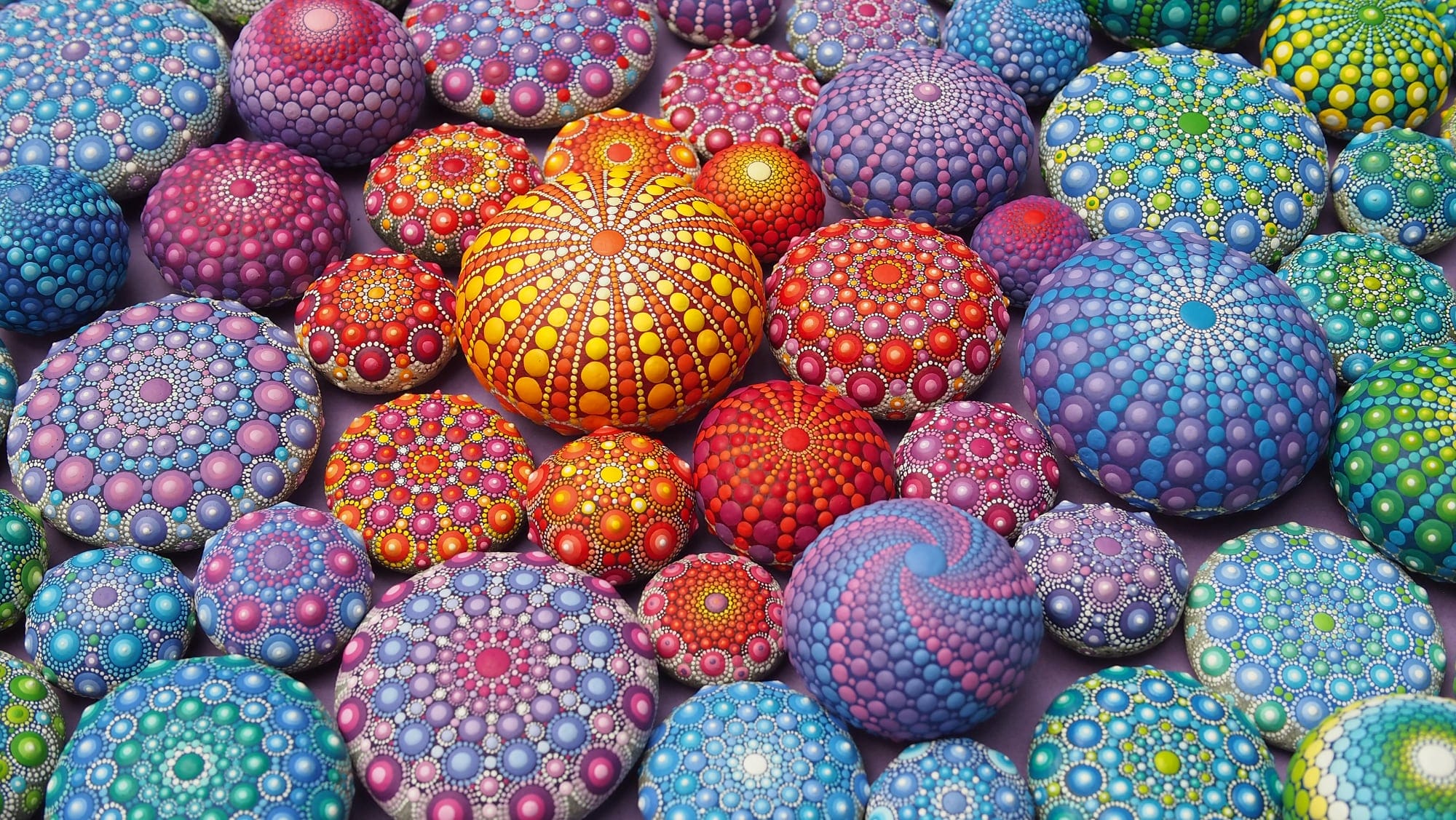 a collection of hand painted rocks in mesmerizing vibrant patters