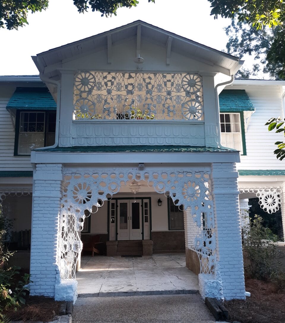 the facade of a Georgia home with an installation around the balcony and entrance made of metal that resembles crochet