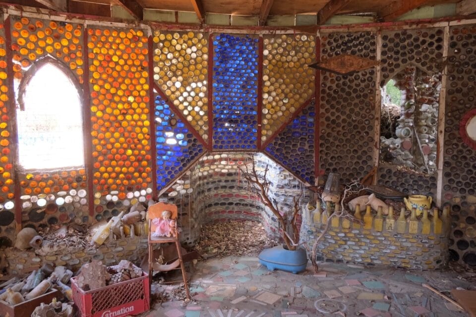 the interior of a unique handmade home in California, where the walls and windows are made of colored bottles