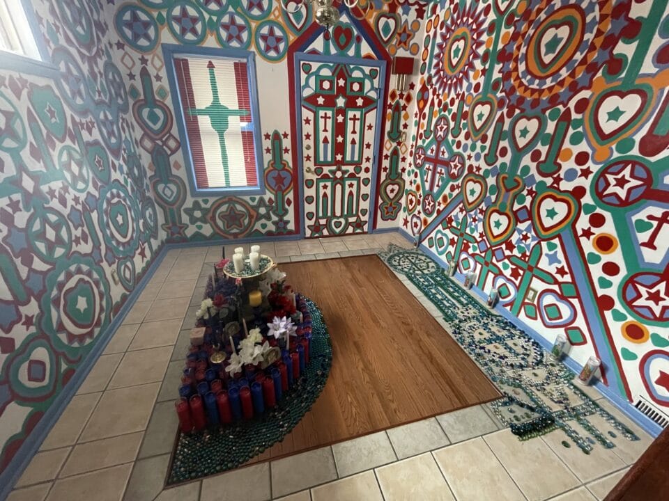 the interior of an artist environment with painted walls inspired by stained glass and an altar in the middle of the room