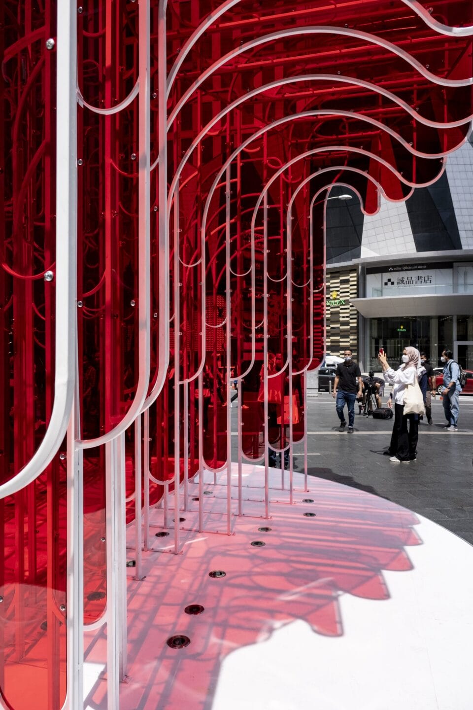 a detail of a vibrantly colored architectural pavilion made of bright red acrylic panels cut into undulating shapes