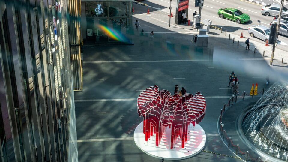 an aerial view of a vibrant red architectural pavilion made of bright red acrylic panels cut into undulating shapes