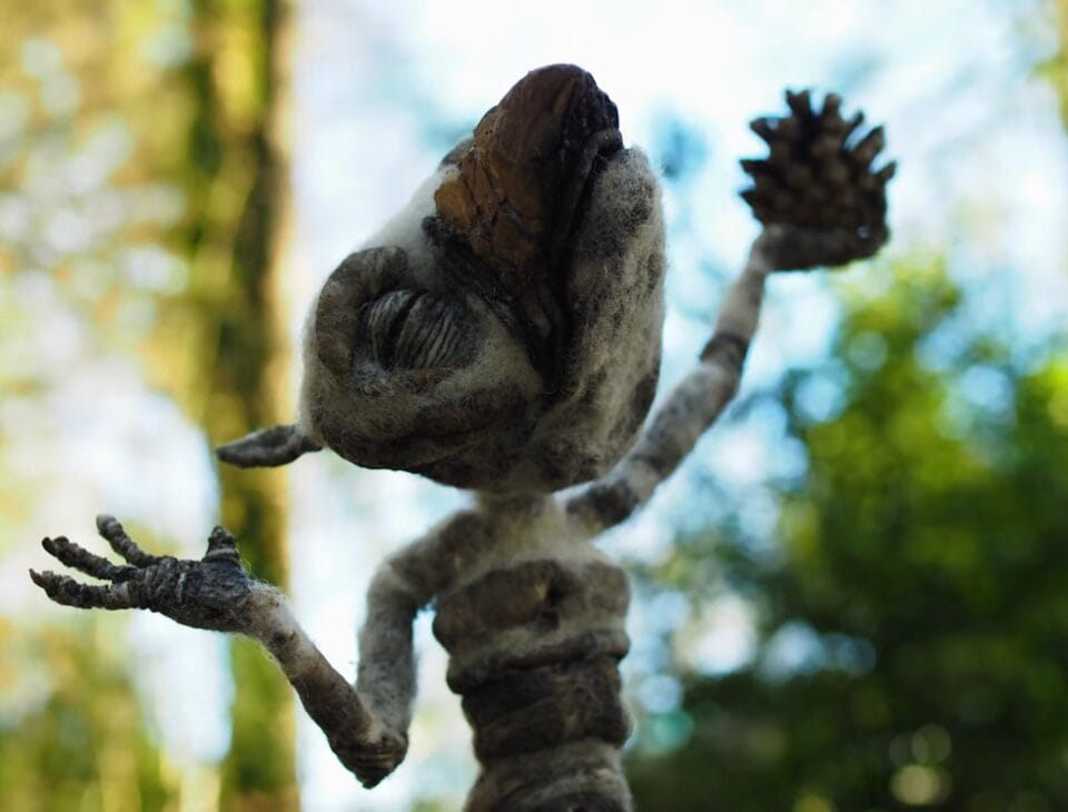 a video still of a felted woodland creature holding a pinceone