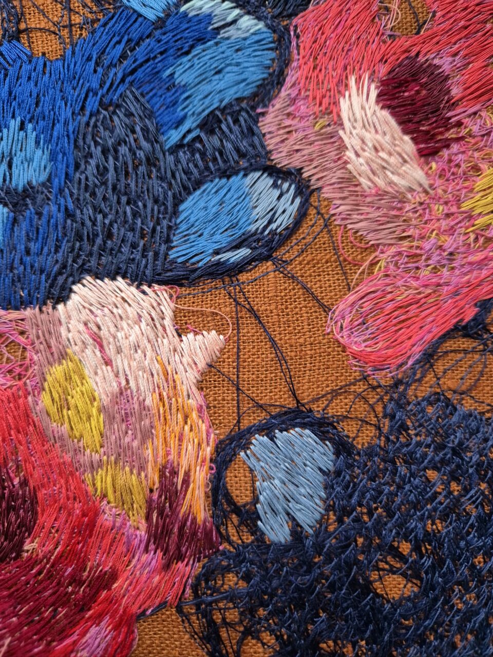 a detail image of a colorful abstract embroidery on brown fabric