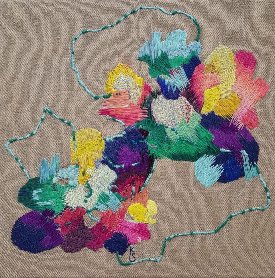 a colorful abstract embroidery on tan fabric