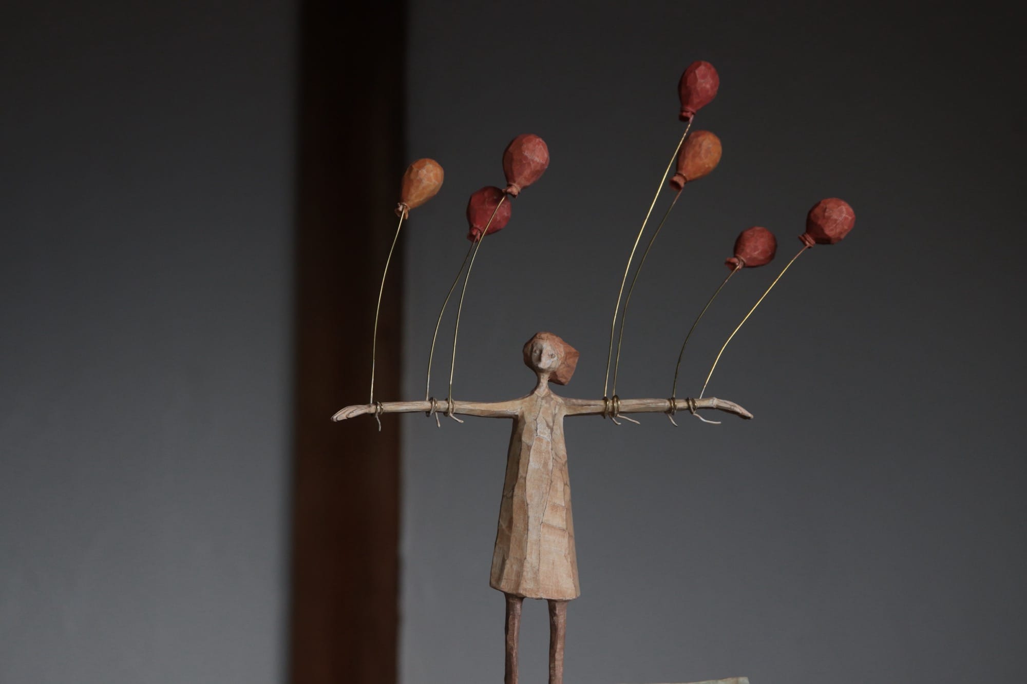 a wooden figure with red balloons attached to her arms